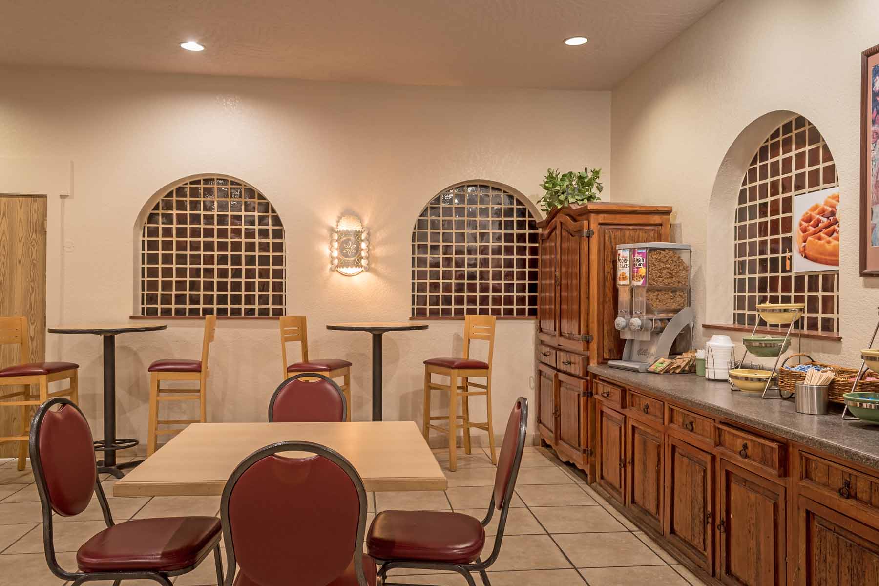 A hotel breakfast area with tables, chairs, and a buffet.
